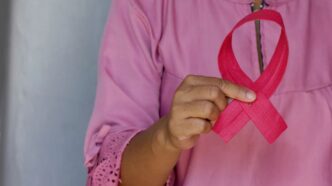 Mulher segura fita cor-de-rosa, símbolo da campanha Outubro Rosa